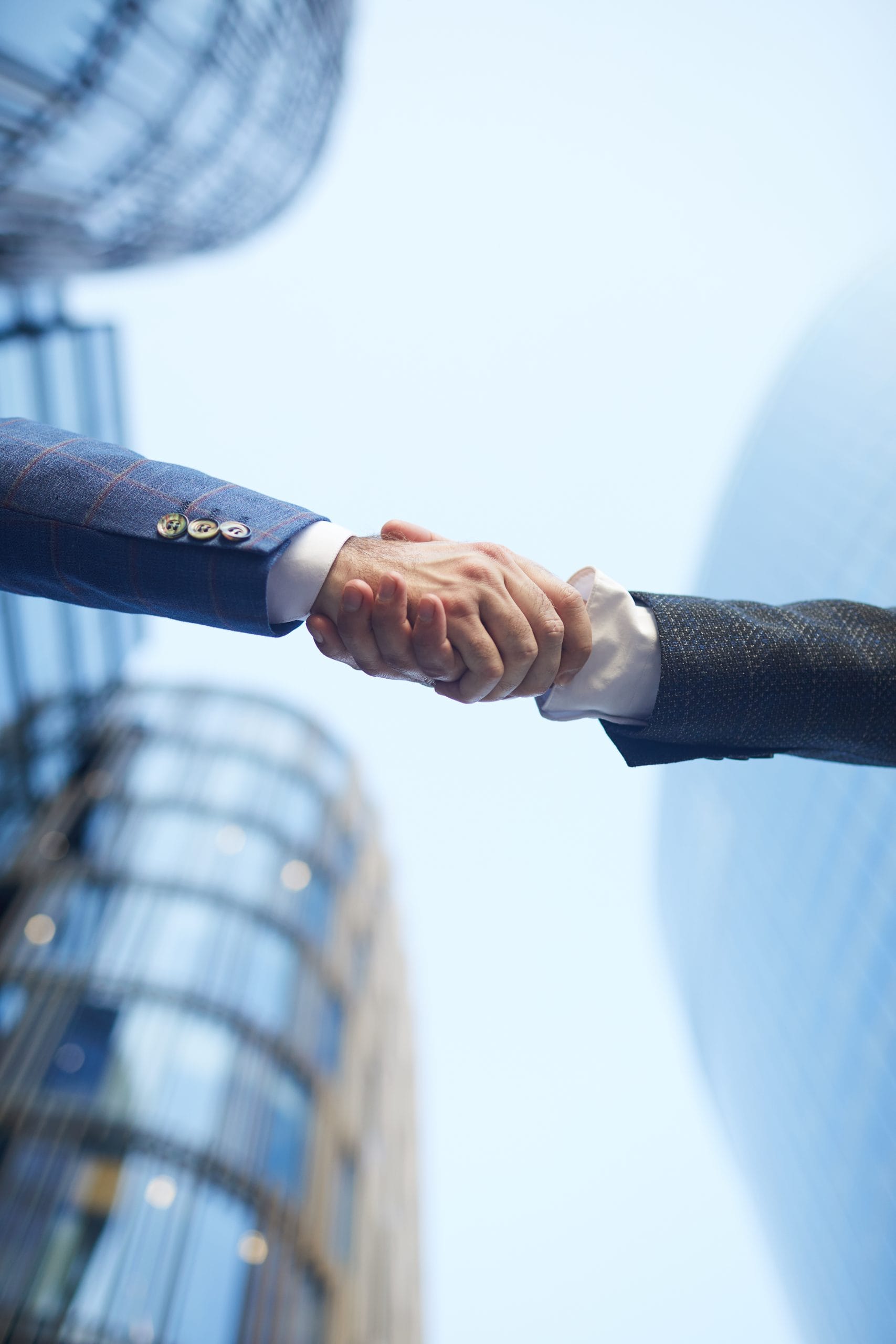 Business handshake outdoors Low angle view of business people shaking hands to each other against the office building outdoors